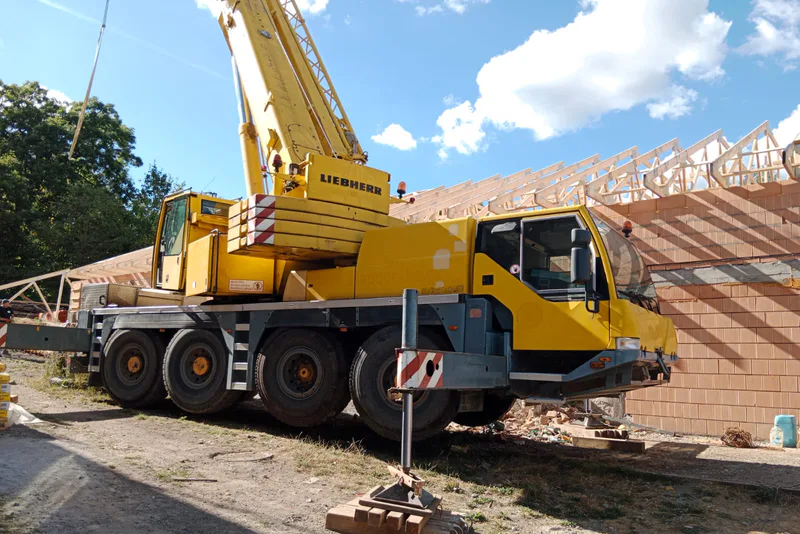 Hrubá stavba rodinného domu s autjeřábem na staveništi